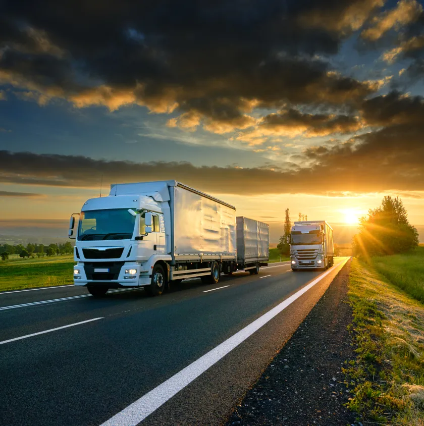 Lorries on an open road at sunset