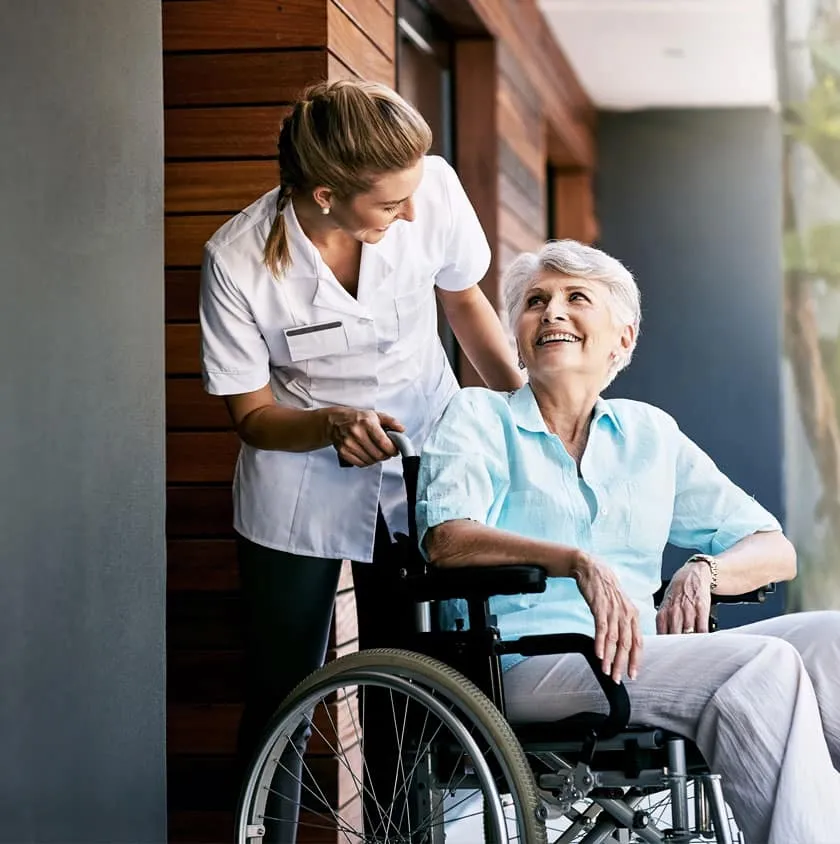 A carer supporting an older woman in a wheelchair