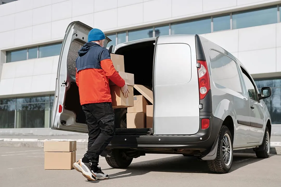 A courier loading parcels into a van